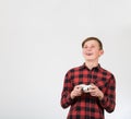 Fascinated teen boy playing video games isolated over white background. Excited adolescent stand all ears holding a joystick