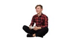 Fascinated teenager boy seated on the floor playing video games isolated on white background. Excited adolescent holding a