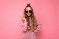 Fascinating dissatisfied adult blonde curly woman over pink background wall wearing casual pink sport clothes