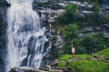 Fascinating low angle shot of a female admiring the waterfall in Doi Inthanon park in Thailand