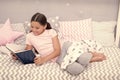 Fascinating story. Girl child lay bed with pillows read book. Kid prepare to go to bed. Time for evening fascinating Royalty Free Stock Photo