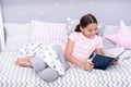 Fascinating story. Girl child lay bed with pillows read book. Kid prepare to go to bed. Time for evening fascinating Royalty Free Stock Photo