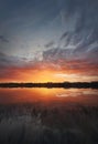 Fascinating sunset reflecting on the lake surface. Idyllic landscape, vertical background. Silent and tranquil evening scene with