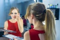 Fashio Portrait of beautiful young girl making make-up near mirror