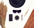 Fashion accessory, female black round hat, sunglasses, screen phone, pocket mirror, red lipstick with dry spikelets plants Royalty Free Stock Photo