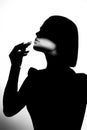 Fashion advertising portrait of a young beautiful girl using lipstick. Black and white silhouette with epic light.