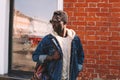Fashion african man in jeans jacket, with backpack walking on city street Royalty Free Stock Photo