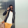 Fashion african man model posing wearing a sunglasses and black rock leather jacket with bag in the city, copy space Royalty Free Stock Photo