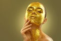 Fashion art Golden skin Woman face portrait closeup. Model girl with cracked gold foil on skin. Glamour shiny professional makeup