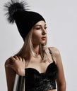 Fashion art portrait of glamour style woman blonde in plush bralet and winter hat standing with her hand at her shoulder Royalty Free Stock Photo