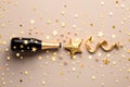 Fashion background with golden champagne bottle, confetti stars, holiday decoration and party streamers in flat lay style. Royalty Free Stock Photo