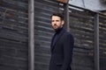 Fashion beard style business handsome male model posing in style clothing blue jacket and trousers on street wooden wall outdoors Royalty Free Stock Photo