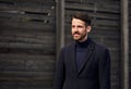 Fashion beard style business handsome male model posing in style clothing blue jacket and trousers on street wooden wall outdoors Royalty Free Stock Photo