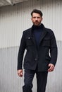 Fashion beard style business handsome male model stepping in style clothing blue jacket and trousers on street wall outdoors Royalty Free Stock Photo