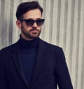 Fashion beard style business handsome male model in fashion sunglasses and blue coat with serious concentrated look posing in Royalty Free Stock Photo