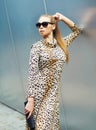 Fashion beautiful blonde woman wearing a leopard dress and sunglasses with handbag clutch Royalty Free Stock Photo