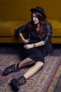 Fashion beautiful middle eastern model with hipster style is posing on carpet and yellow sofa. Royalty Free Stock Photo