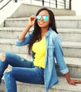 Fashion beautiful smiling african woman wearing a sunglasses and jeans clothes in the city Royalty Free Stock Photo