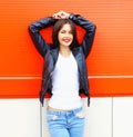 Fashion beautiful smiling young woman wearing rock black jacket, jeans in the city over colorful red Royalty Free Stock Photo