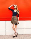 Fashion beautiful woman in leopard skirt sunglasses with handbag clutch over red Royalty Free Stock Photo