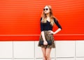 Fashion beautiful woman in leopard skirt sunglasses handbag clutch posing over colorful red Royalty Free Stock Photo