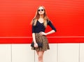 Fashion beautiful woman in leopard skirt sunglasses handbag clutch posing over red colorful Royalty Free Stock Photo