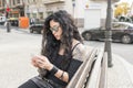 Fashion beautiful woman with smart phone sitting on bench.