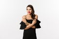 Fashion and beauty. Beautiful glamour woman in black dress, making choice, biting lip from temptation and pointing Royalty Free Stock Photo