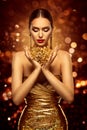 Fashion Beauty Model holding Golden Jewelry Flowers in Hands. Woman Face Hand Skin Care and Cosmetic over Shining Lights Royalty Free Stock Photo