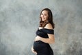 Fashion beauty portrait of happy pregnant woman in black dress on gray background Royalty Free Stock Photo