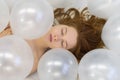 Fashion beauty portrait of young sensual redhead woman with dreamily closed eyes between white iridescent balloons Royalty Free Stock Photo