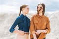 Fashion beauty portrait of young women sisters in brown organic velvet jeans shirts on desert background