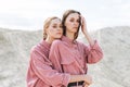 Fashion beauty portrait of young women sisters in pink organic velvet shirts on desert background