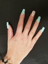 hand of woman with nails decorated in aquamarina color and black background