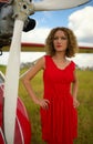 Fashion beautyful woman in red dress nearby ultralight plane Royalty Free Stock Photo