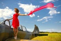 Fashion beautyful woman in red dress stays on a wing of the old plane Royalty Free Stock Photo