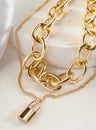 Fashion bijouterie - double gold chain with a lock on a white stand Royalty Free Stock Photo