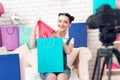 Fashion blogger girl with make up pulls item from colorful bag to camera.