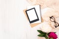 Fashion blogger home office desk with woman items : modern e-book reader, paper notepad, beige scarf, peonies flowers, glasses.