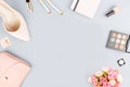 Fashion blogger workspace flat lay with pumps, cosmetics, purse, planner book and flowers.