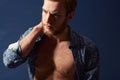 Fashion, body or model with muscle in studio on a blue background wearing an open unbuttoned shirt. Thinking, chest or Royalty Free Stock Photo