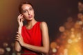 Fashion brunette woman in red dress and gold earrings. Touching your hand to your face. Lights in the background Copycpase Royalty Free Stock Photo