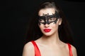 Fashion brunette woman with red lips makeup wearing carnival mask on black background, halloween portrait Royalty Free Stock Photo