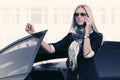 Fashion business woman in sunglasses talking on cell phone leaning on car door Royalty Free Stock Photo