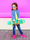 Fashion child little girl with skateboard on colorful pink wall Royalty Free Stock Photo