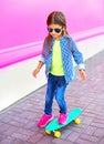 Fashion child little girl on skateboard on colorful pink wall Royalty Free Stock Photo