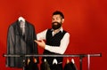 Fashion choice. Man with beard in vest by clothes rack.