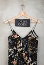 Fashion concept - blackboard with text Dress code and beautiful dress in floral pattern on a hanger