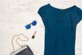 Fashion concept. Blue blouse, round glasses, lipstick and part of handbag. Top view Royalty Free Stock Photo