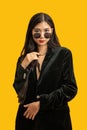 Fashion concept, Fashionable woman wear black coat and sunglasses to posing over yellow background Royalty Free Stock Photo